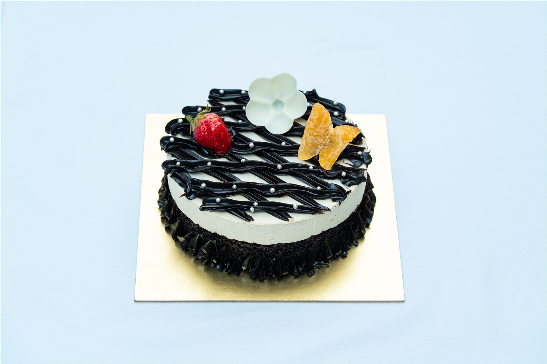 Black and white decorated cake with fruit topping